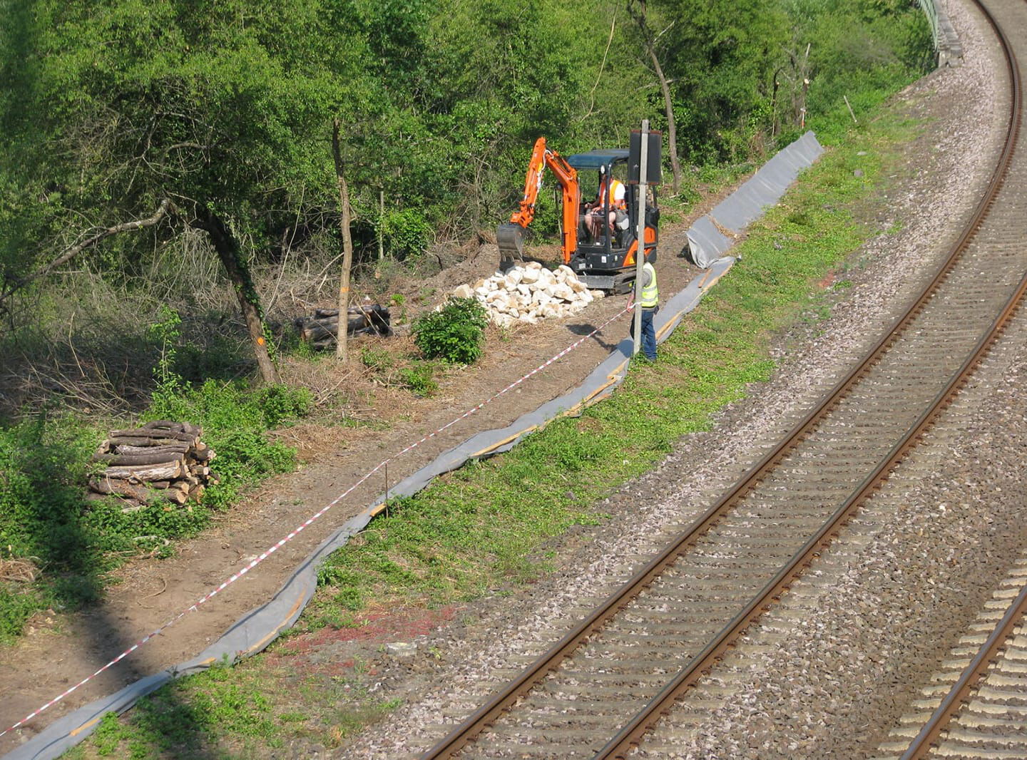 Am Wegrand der Bahngleisen steht ein Bagger