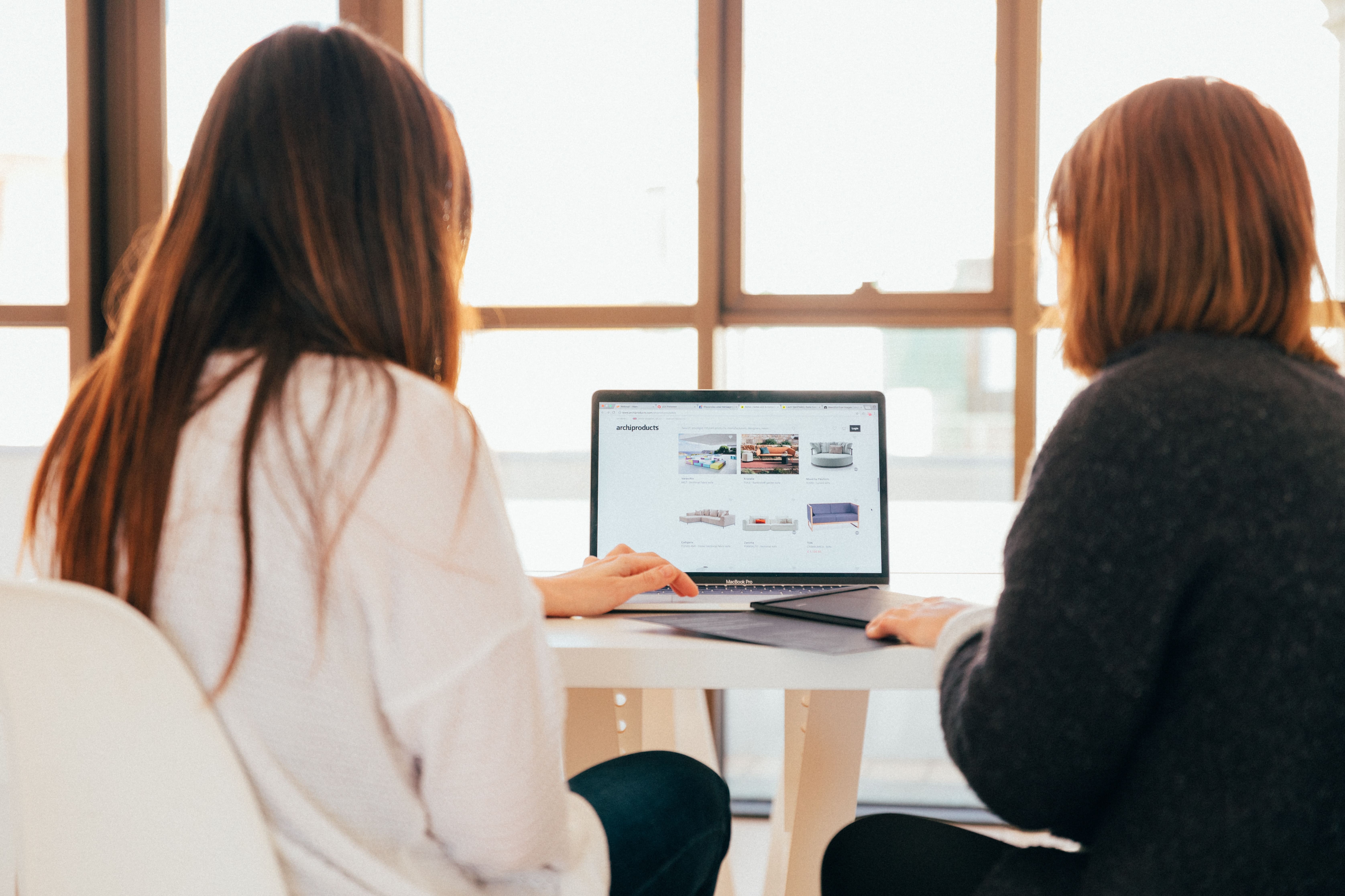 zwei Frauen sitzen vor dem Laptop